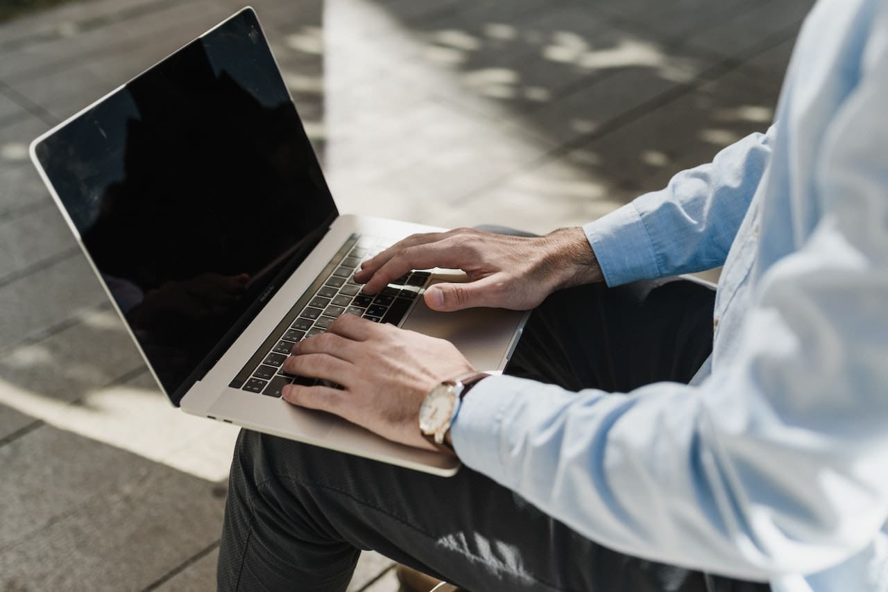 A person sitting on the ground with a laptop.